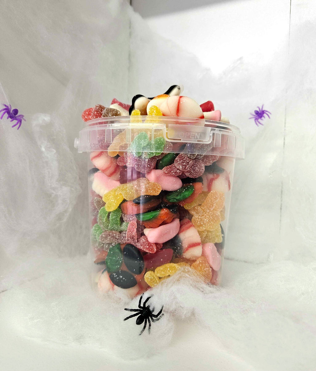 Clear container filled with colorful gummy candies on a Halloween-themed background with spider webs and spiders.